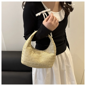 Detail of hand-woven beige crescent handbag showing textured straw material and size