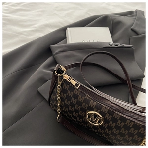 Dettaglio borsa a mezzaluna monogramma marrone scuro con logo dorato su blazer grigio