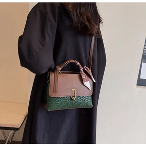 Detailed view of bicolor woven handbag with golden buckle and patterned silk scarf handle