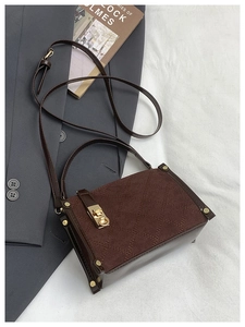 Detail of dark brown quilted crossbody bag with gold twist-lock and metal feet