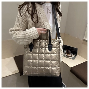 Macro detail of champagne gold quilted tote bag with black strap and metallic finish