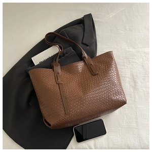 Dettaglio della borsa tote intrecciata marrone con motivo Intrecciato e tracolle