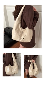 Detail of cream white tote bag with silver metal studs in a star pattern and wide strap