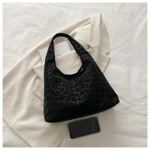 Detail of black leopard print tote bag with soft velvet texture on white suit background