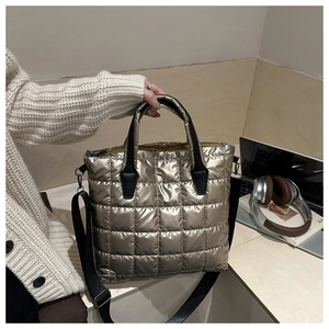 Detail of gold quilted tote bag with metallic finish and black adjustable shoulder strap