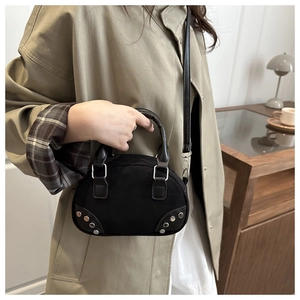 Detail of black mini suede crossbody bag with silver rivets and leather strap