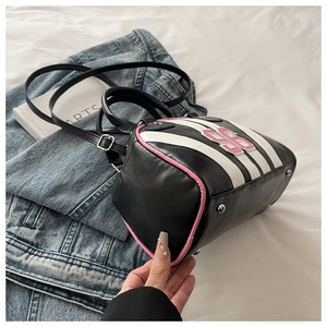 Detail of a black mini Boston bag with white stripes, pink 95 patch, and protective base studs