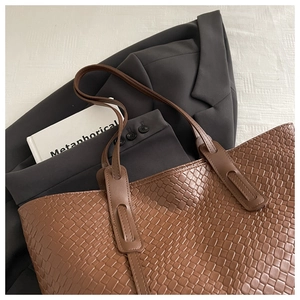 Dettaglio della borsa tote in pelle PU intrecciata marrone con doppi spallacci lunghi su stoffa