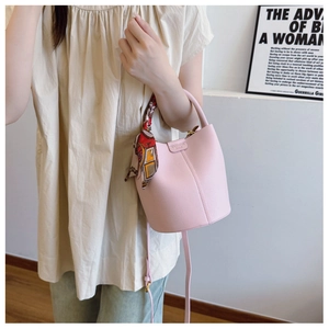 Detailed macro of pink lychee textured bucket bag with silk scarf handle and metal logo
