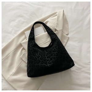 Detail of black leopard print tote bag placed on white bedding with a blazer