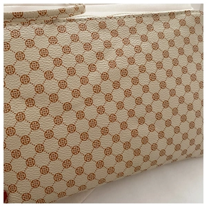 Detail of clover monogram pattern on white lychee grain leather envelope clutch bag