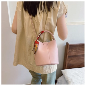 Close-up of pink litchi grain leather bucket bag with silk scarf on handle