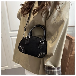 Close-up of black crossbody bag with silver rivet details and matte suede texture