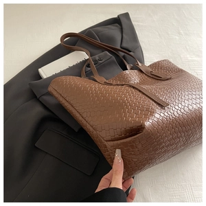 Dettaglio di borsa tote in pelle intrecciata marrone scuro con texture a trama larga