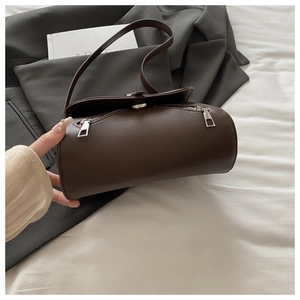 Close-up of deep brown cylindrical shoulder bag with premium glossy leather and silver zippers