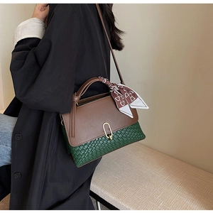 Detail of a brown and green leather handbag with a patterned scarf and gold clasp