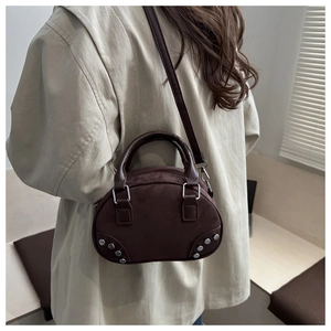 Detail of dark brown suede shell bag with silver rivets and adjustable shoulder strap