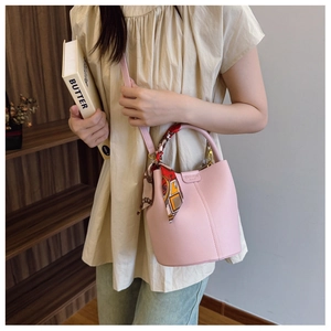 Close-up of pink lychee leather bucket bag featuring a decorative printed silk scarf handle
