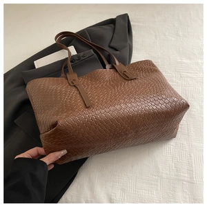 Dettaglio della trama intrecciata a mano della borsa tote in pelle marrone per lavoro e vita