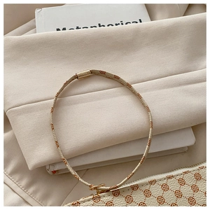 Close-up of floral print cord necklace with gold lobster clasp and matching bag