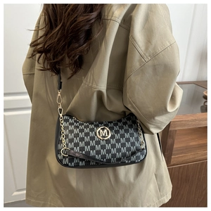 Dettaglio della borsa sottobraccio chic con motivi M jacquard e catena dorata su modella