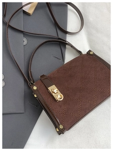 Detail of dark brown quilted handbag with gold twist lock and metallic studs