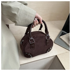 Detail of dark brown suede mini boston bag with silver buckles and metal rivets
