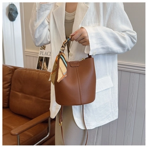 Brown litchi grain bucket bag detail with silk scarf handle and leather shoulder strap