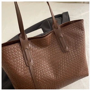 Dettaglio della trama intrecciata e del manico in pelle rinforzata della borsa marrone