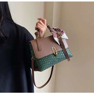 Detail of green woven texture handbag with brown leather flap and silk scarf handle
