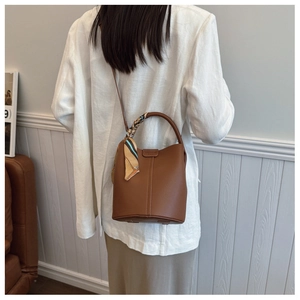 Detail of a brown lychee pattern leather bucket bag featuring a vintage decorative silk scarf