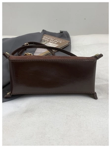 Detail shot of a dark brown square bag showing smooth leather and suede bottom texture