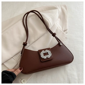 Detail of a dark brown baguette bag featuring a shiny rhinestone buckle and knotted strap