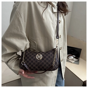 Close-up of brown monogram crescent bag with golden M logo and metallic chain strap