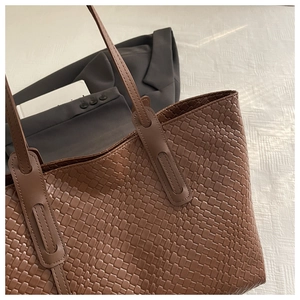 Dettaglio della borsa tote in pelle intrecciata marrone con trama fine e tracolla lunga