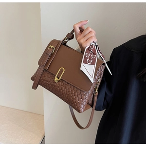 Close-up of dark brown woven leather handbag with gold U-buckle and elegant silk scarf handle