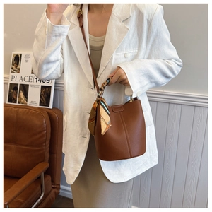 Brown lychee leather bucket bag with silk scarf handle detail and long shoulder strap