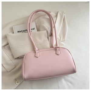 Detail view of pink leather shoulder bag with gold hardware on beige blazer background