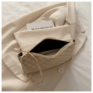 Detail view of beige monogram shoulder bag with matching inner pouch on a chic blazer
