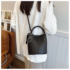 Detail of black lychee leather bucket bag with decorative scarf on handle and shoulder strap