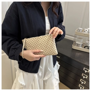 Macro view of beige envelope clutch bag with geometric pattern and metallic zipper detail