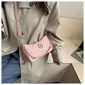 Borsa a spalla rosa con monogramma e catena d'oro, indossata con un cappotto beige
