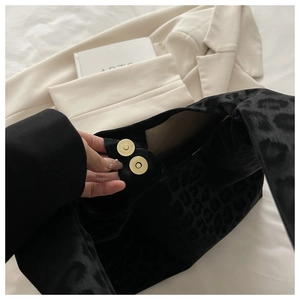 Close-up of black leopard print tote bag with golden magnetic buckles and velvet texture