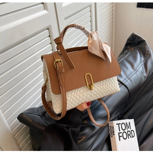 Detailed view of bicolor handbag featuring woven texture and decorative silk scarf handle