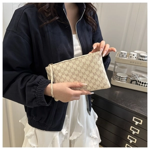 Close-up of beige wristlet bag with brown M pattern print and elegant metal zipper