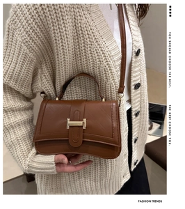 Detail of caramel faux leather bag featuring a gold I-shaped metal buckle and shoulder strap