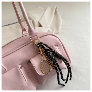 Pink Boston bag detail featuring three functional flap pockets and a gold tennis racket charm