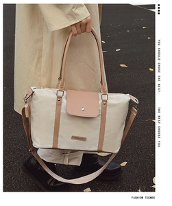 Detail of canvas tote bag with brown leather straps and metal logo in outdoor setting