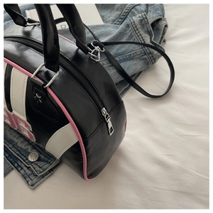Detail of Boston handbag with pink edge paint, 86 embroidery, and zipper on denim background