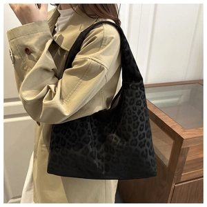 Close-up of black tote bag featuring subtle leopard print and glossy velvet texture